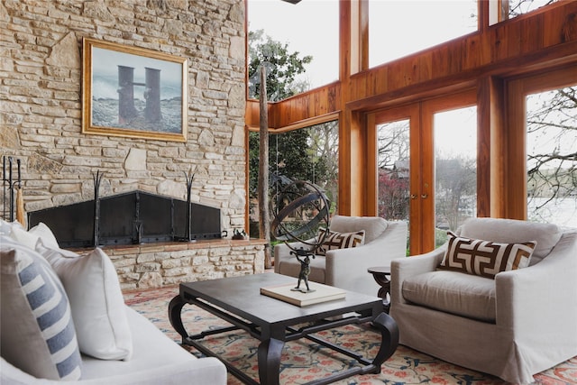 living room featuring a high ceiling, french doors, a fireplace, and wood walls