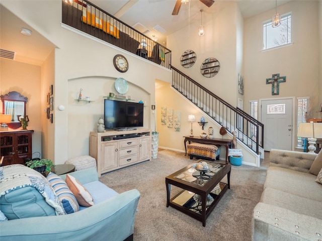 carpeted living room with ceiling fan and a high ceiling