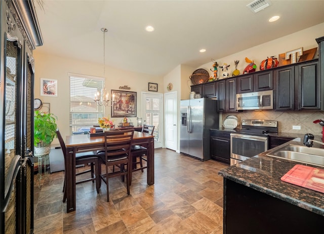 kitchen featuring appliances with stainless steel finishes, backsplash, a chandelier, pendant lighting, and sink