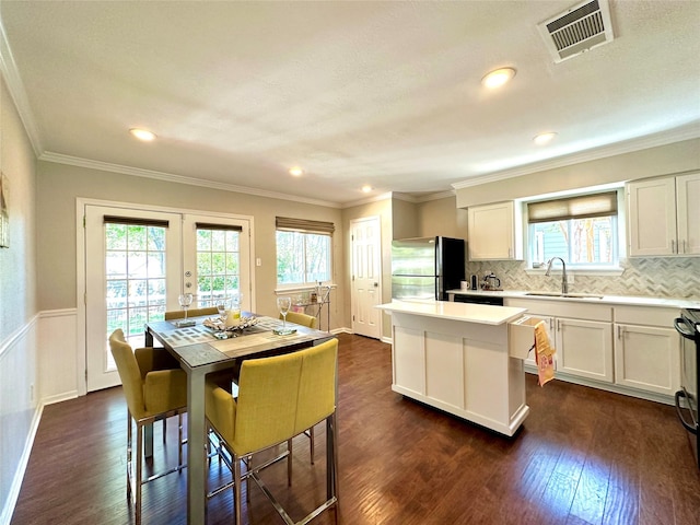 kitchen featuring sink, stainless steel refrigerator, a center island, white cabinets, and french doors