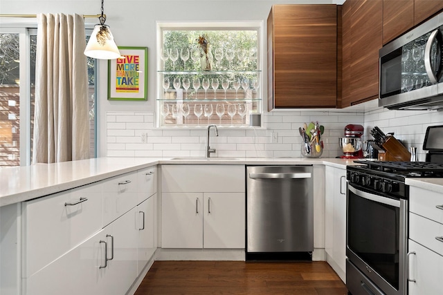 kitchen featuring decorative light fixtures, decorative backsplash, white cabinets, and stainless steel appliances