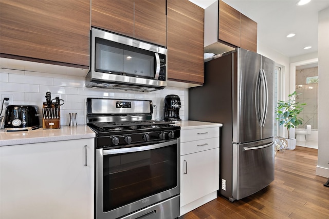 kitchen featuring decorative backsplash, wood-type flooring, and appliances with stainless steel finishes