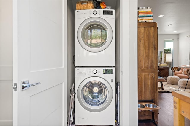 laundry area featuring stacked washer and dryer and dark wood-type flooring