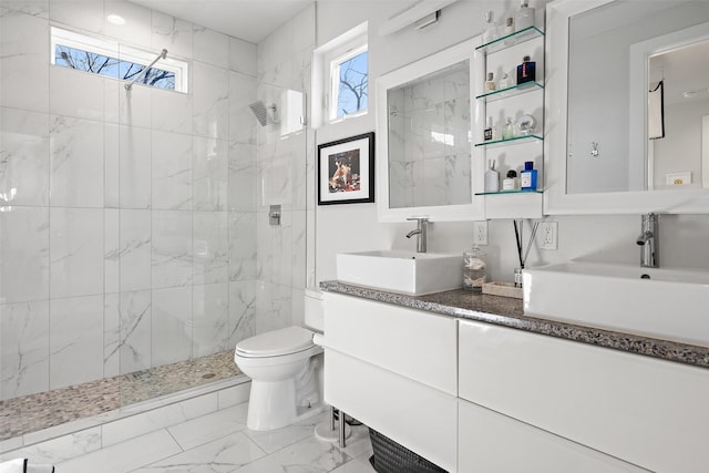 bathroom with toilet, tiled shower, and vanity