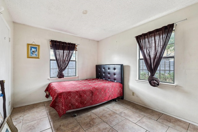 bedroom featuring multiple windows, a textured ceiling, and light tile patterned flooring