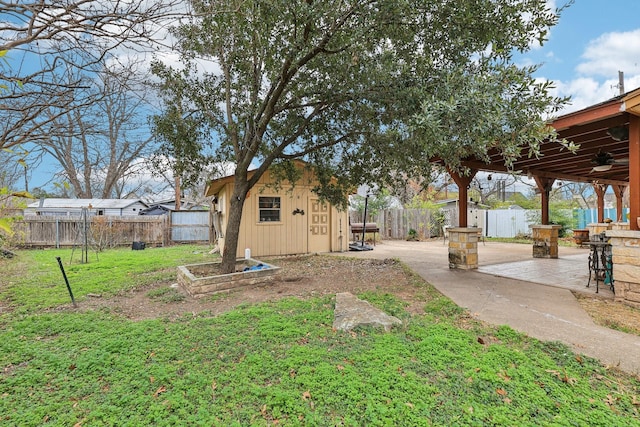 view of yard featuring ceiling fan, a shed, and a patio