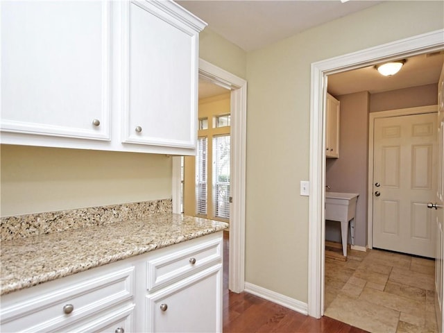 kitchen with hardwood / wood-style flooring, light stone countertops, and white cabinets