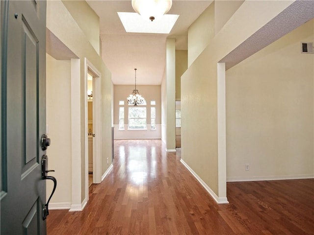 corridor featuring wood-type flooring, a chandelier, and a high ceiling