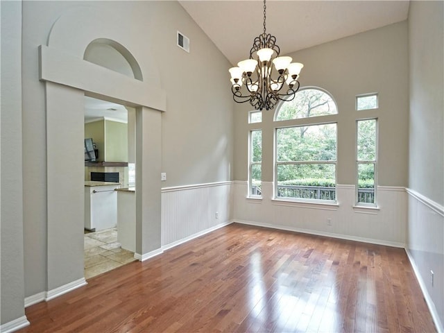 spare room with light wood-type flooring, a chandelier, and lofted ceiling