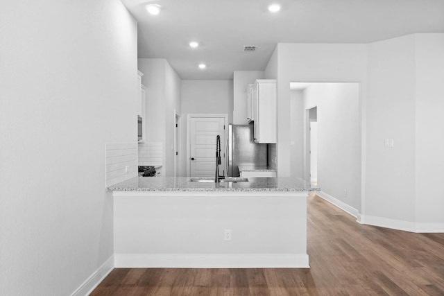 kitchen featuring tasteful backsplash, white cabinets, kitchen peninsula, and stainless steel refrigerator