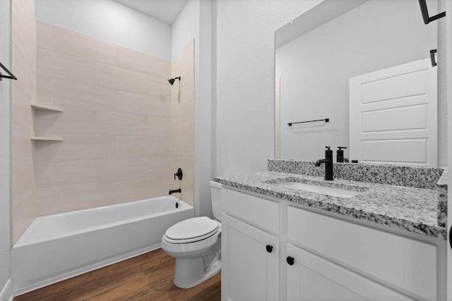 full bathroom with wood-type flooring, tiled shower / bath combo, vanity, and toilet