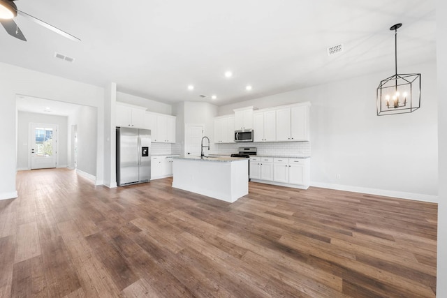 kitchen featuring white cabinets, appliances with stainless steel finishes, sink, and an island with sink