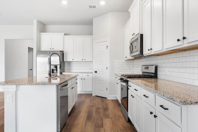 kitchen with stainless steel appliances, white cabinets, and a center island with sink