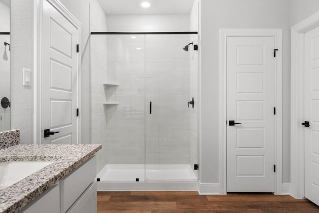 bathroom with a shower with shower door, vanity, and hardwood / wood-style floors