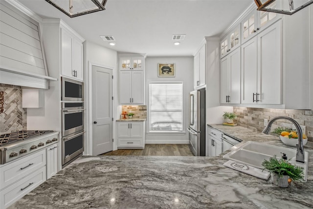 kitchen with white cabinetry, appliances with stainless steel finishes, light stone countertops, and sink