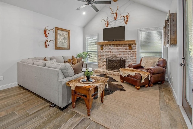 living room featuring high vaulted ceiling, a fireplace, light hardwood / wood-style floors, and ceiling fan