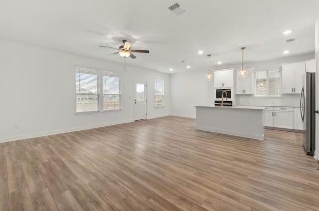 unfurnished living room featuring ceiling fan and light hardwood / wood-style flooring