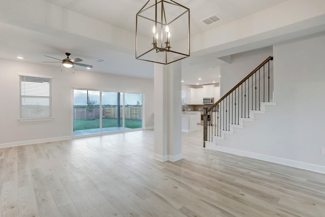 unfurnished living room with ceiling fan with notable chandelier, light hardwood / wood-style floors, and sink