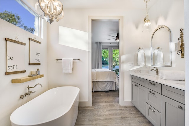 bathroom featuring vanity, a tub, ceiling fan with notable chandelier, and hardwood / wood-style flooring