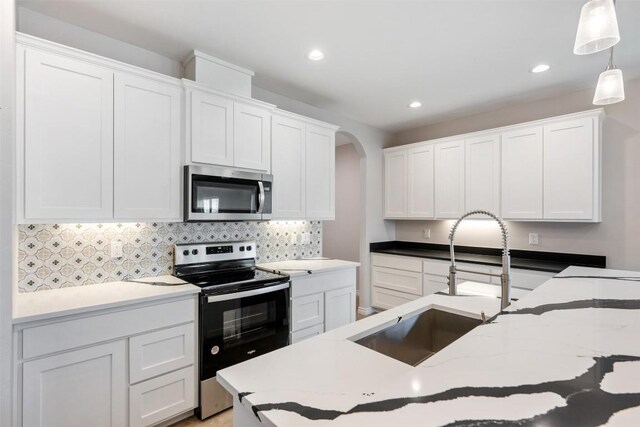 kitchen featuring decorative light fixtures, white cabinets, and stainless steel appliances