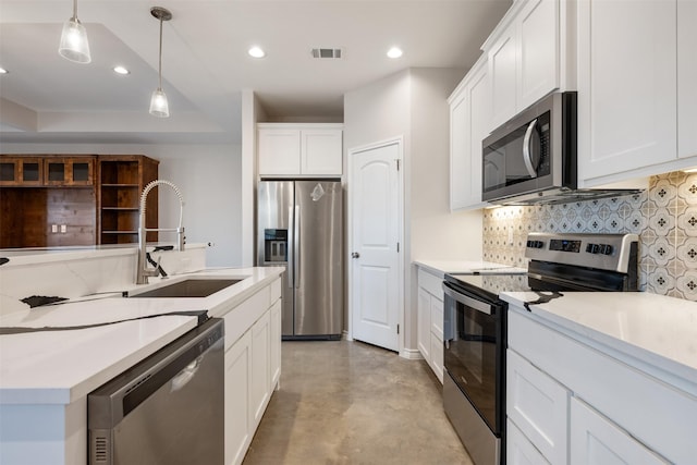 kitchen featuring pendant lighting, sink, white cabinetry, backsplash, and stainless steel appliances