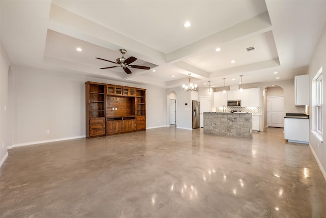 unfurnished living room with ceiling fan, coffered ceiling, and a tray ceiling