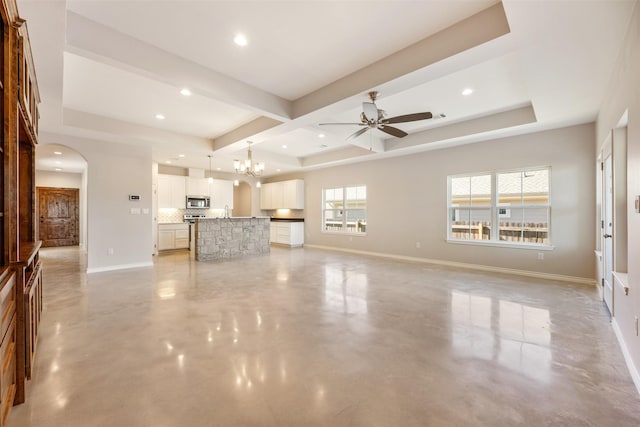 unfurnished living room featuring ceiling fan with notable chandelier, a raised ceiling, beamed ceiling, and coffered ceiling