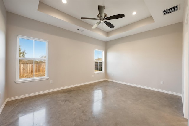 spare room with ceiling fan, concrete floors, and a raised ceiling