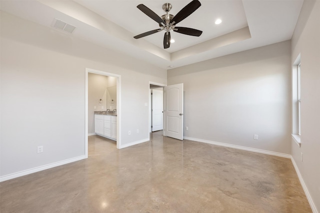 unfurnished bedroom featuring ceiling fan, a tray ceiling, and connected bathroom