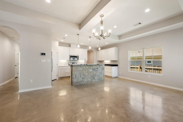 kitchen with white cabinetry, an inviting chandelier, decorative backsplash, hanging light fixtures, and a kitchen island with sink