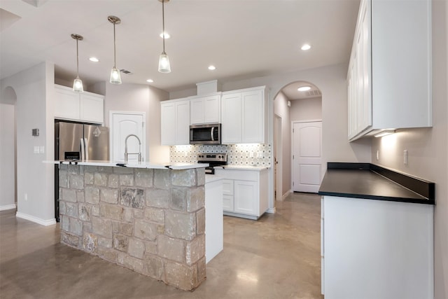 kitchen featuring pendant lighting, white cabinetry, stainless steel appliances, sink, and a center island with sink