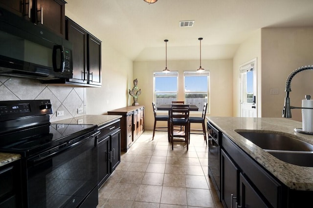 kitchen featuring decorative backsplash, hanging light fixtures, black appliances, light stone counters, and sink