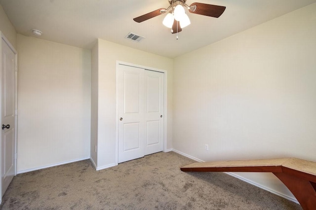 unfurnished bedroom with ceiling fan, carpet flooring, and a closet