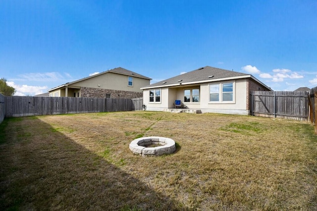 rear view of house with an outdoor fire pit and a yard