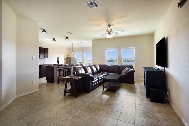 living room featuring ceiling fan, light tile patterned floors, and sink