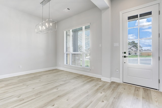 foyer entrance with an inviting chandelier and light hardwood / wood-style floors