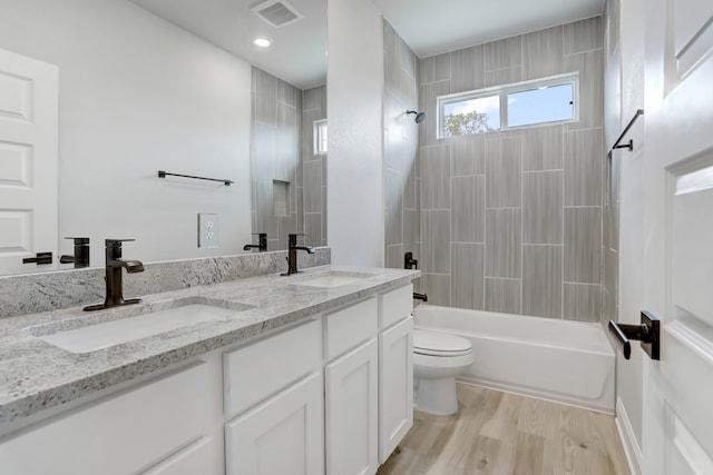 full bathroom with toilet, tiled shower / bath combo, hardwood / wood-style flooring, and vanity