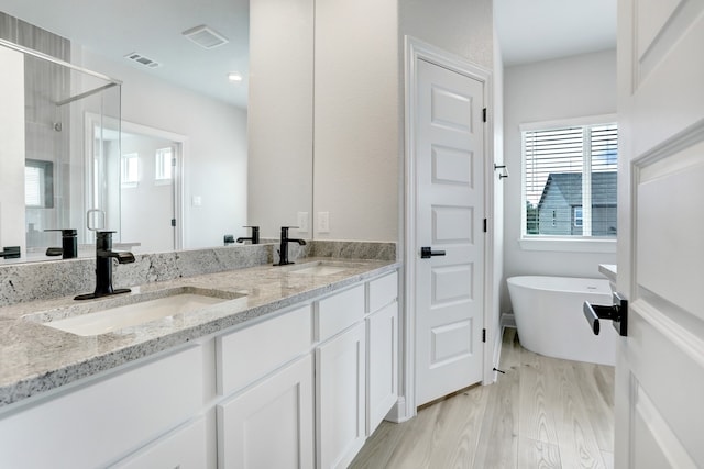 bathroom featuring hardwood / wood-style flooring, vanity, and shower with separate bathtub