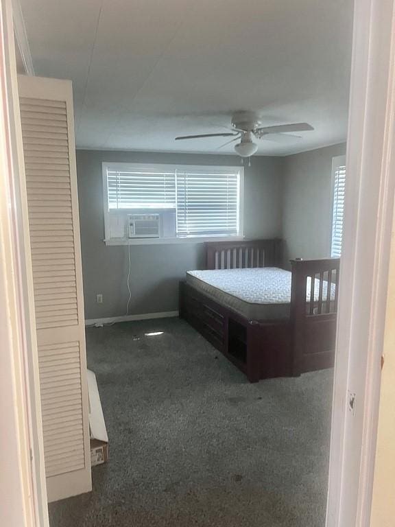 unfurnished bedroom with ceiling fan and dark colored carpet