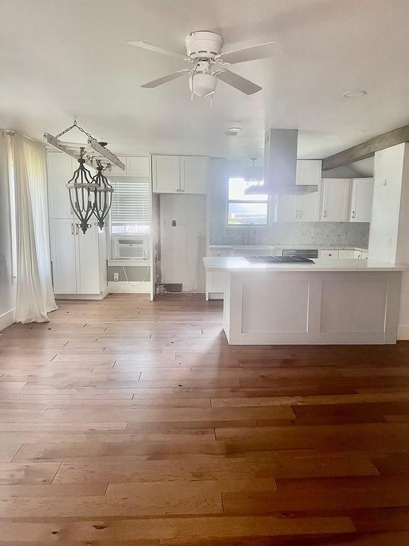 kitchen featuring light wood-type flooring, ceiling fan, white cabinetry, and island range hood