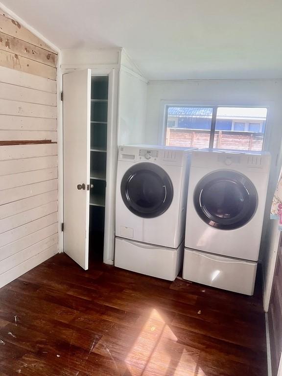 clothes washing area with dark hardwood / wood-style floors, independent washer and dryer, and wooden walls