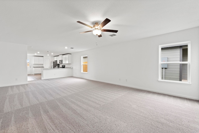 unfurnished living room with ceiling fan and light colored carpet