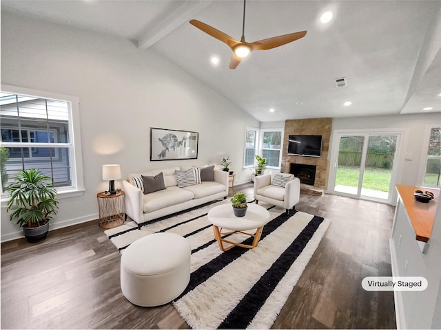 living room with hardwood / wood-style flooring, beamed ceiling, high vaulted ceiling, and a stone fireplace