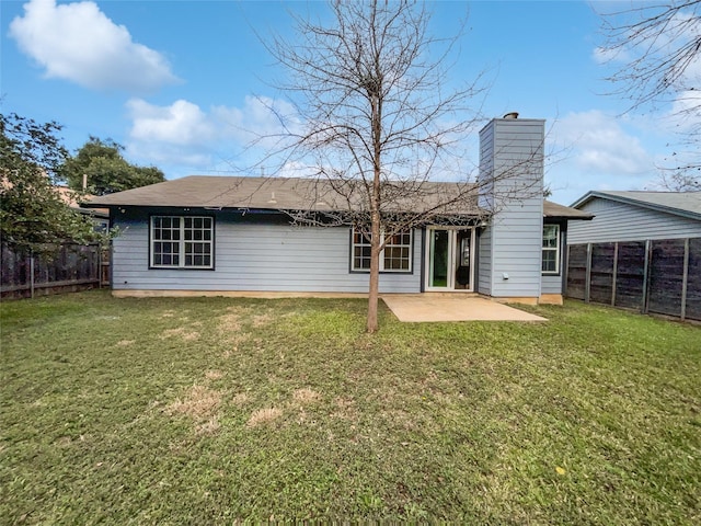 rear view of house featuring a lawn and a patio