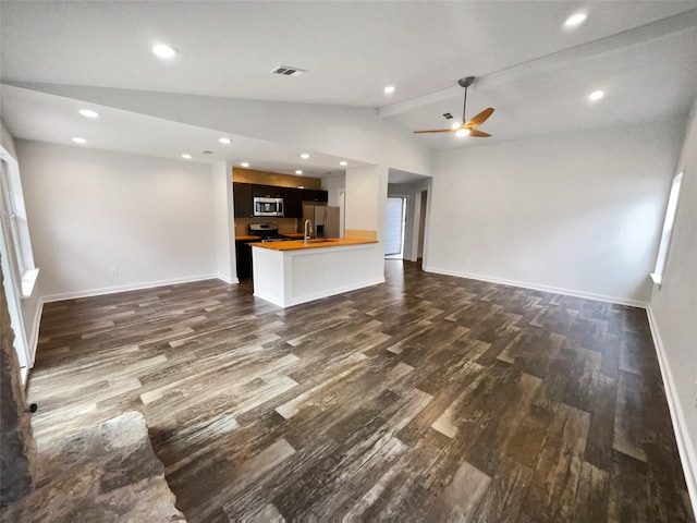 unfurnished living room with ceiling fan, vaulted ceiling with beams, and dark wood-type flooring