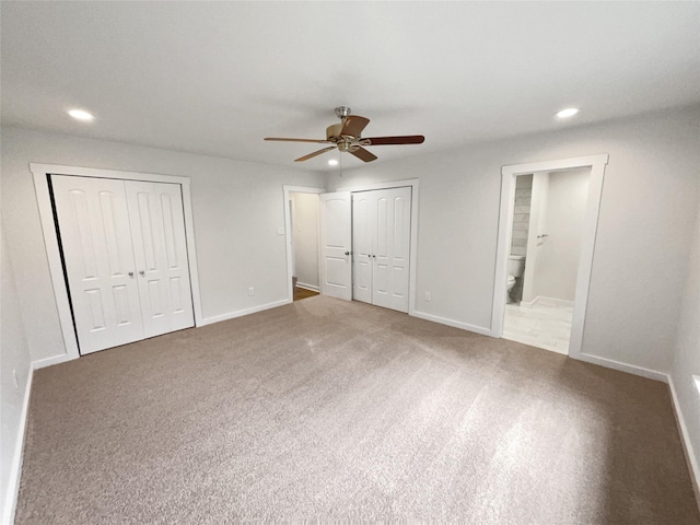 unfurnished bedroom with ceiling fan, two closets, carpet, and ensuite bath