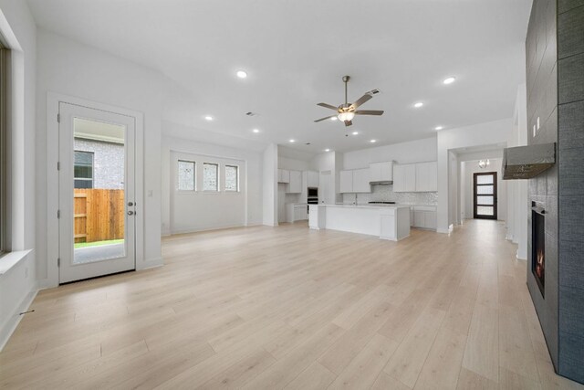 295 Five Mile Creek Way, Kyle, TX 78640 - unfurnished living room featuring a ceiling fan, a fireplace, light wood-style flooring, recessed lighting, and baseboards