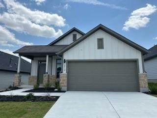 212 Hidalgo Ln, Elgin, TX 78621 - view of front of house featuring an attached garage, driveway, board and batten siding, and stone siding