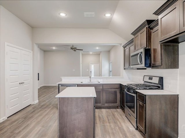 212 Hidalgo Ln, Elgin, TX 78621 - kitchen featuring appliances with stainless steel finishes, a sink, a peninsula, a ceiling fan, and light countertops