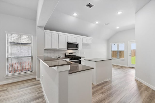212 Hidalgo Ln, Elgin, TX 78621 - kitchen with stainless steel appliances, dark countertops, light wood finished floors, tasteful backsplash, and lofted ceiling